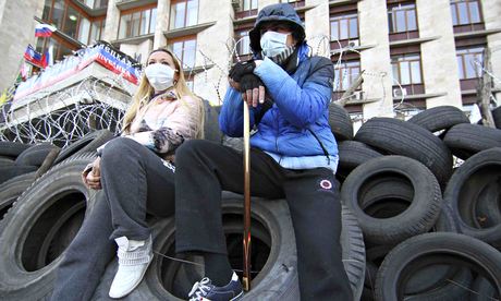 Pro-Russia protesters sit on tyres outside a regional government building in Donetsk
